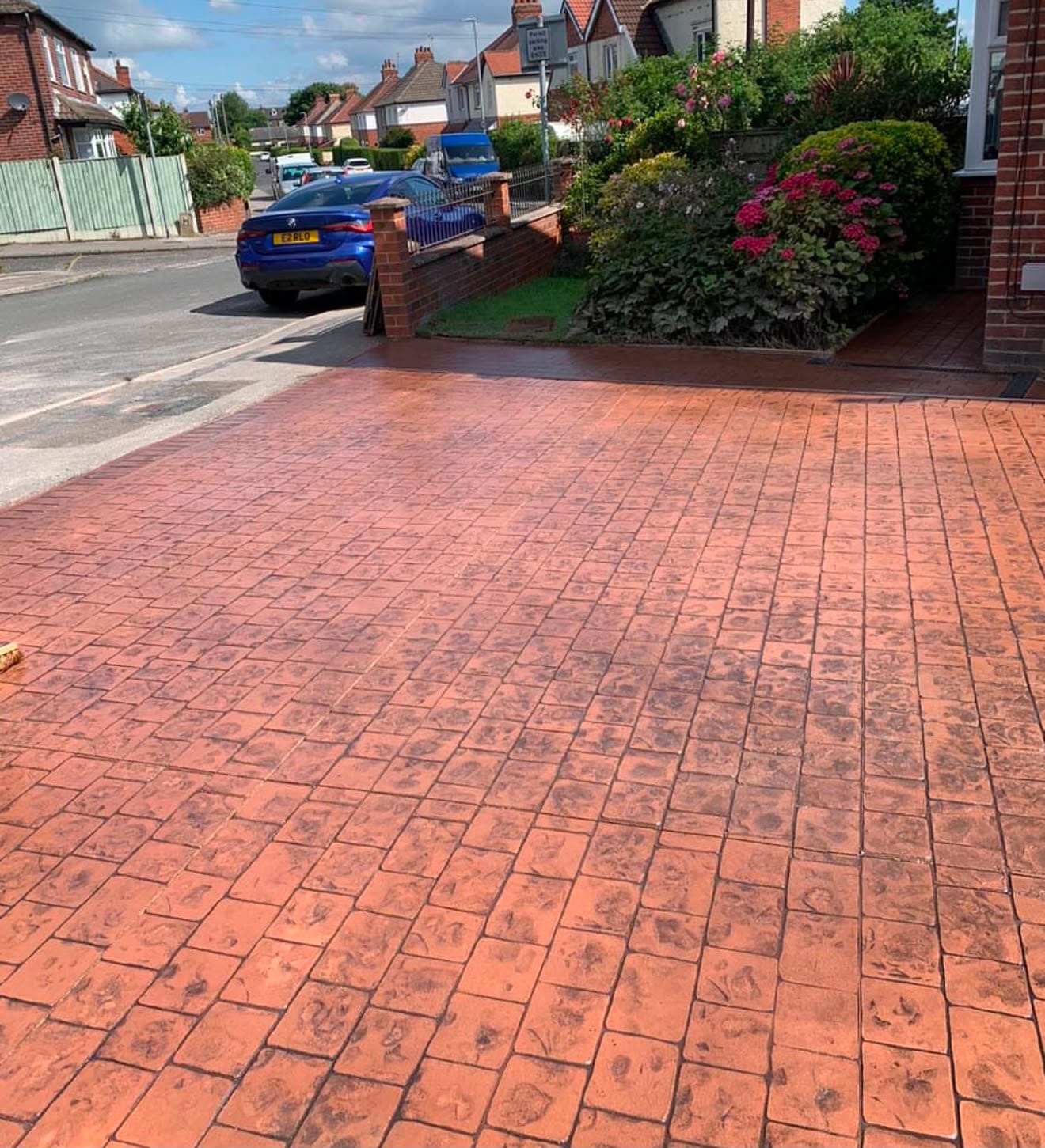 Brindle imprinted concrete driveway running down to the street past a planted border of hydrangeas in summer